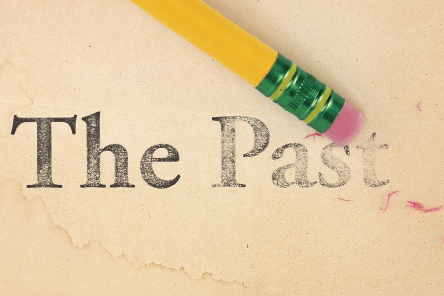 Image of eraser end of pencil to tea stained paper removing the words "The Past". 