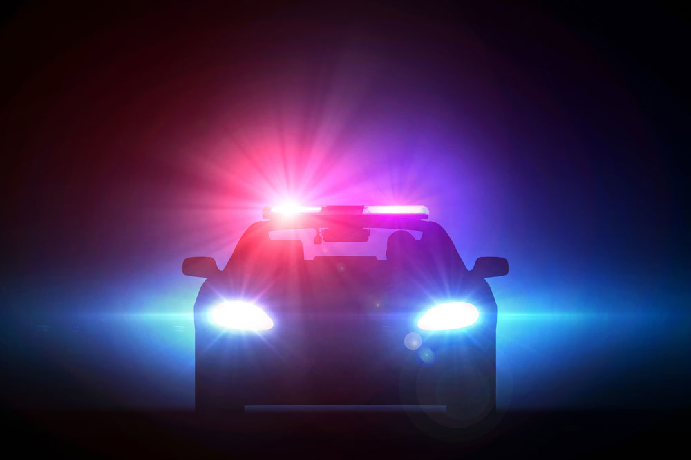 Image of police car's emergency lights cutting through the night depciting interaction with law enforcement during a traffic stop.